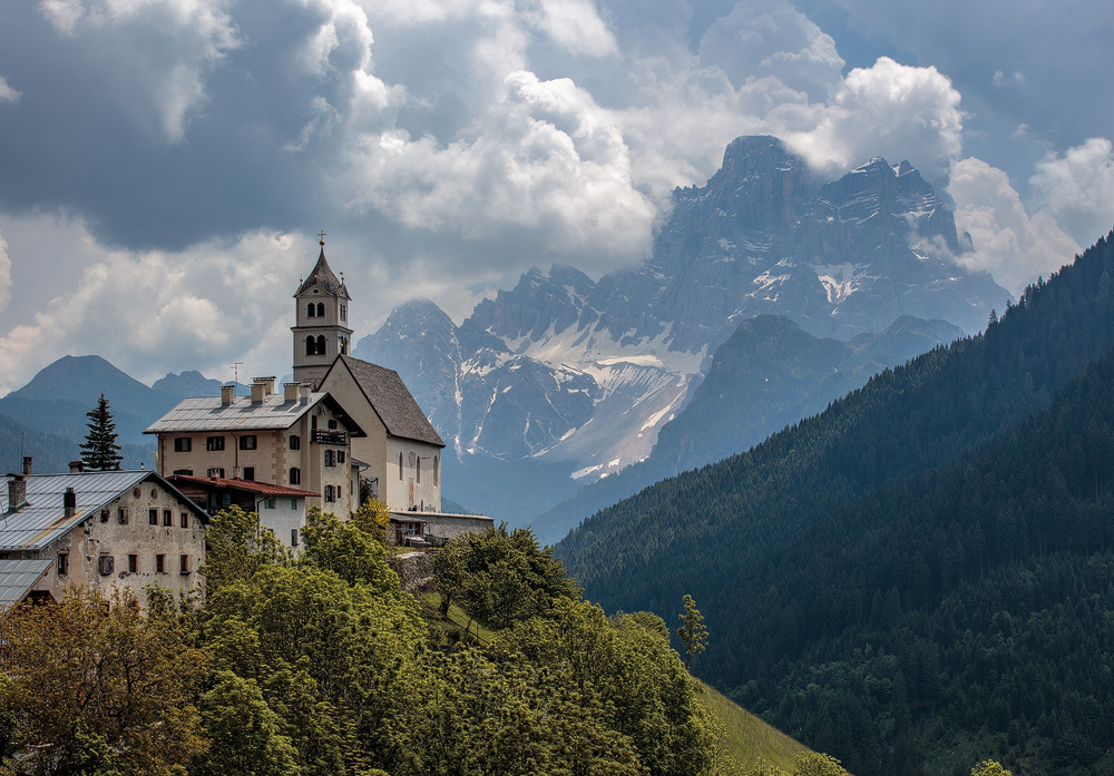 Die Kirche von Colle St. Lucia mit dem Monte Pelmo im Hintergrund. Die Wolken kündigen ein baldiges Gewitter an.